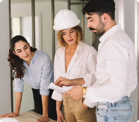 Tres personas en una obra de construcción revisando planos y discutiendo detalles del proyecto en un ambiente moderno